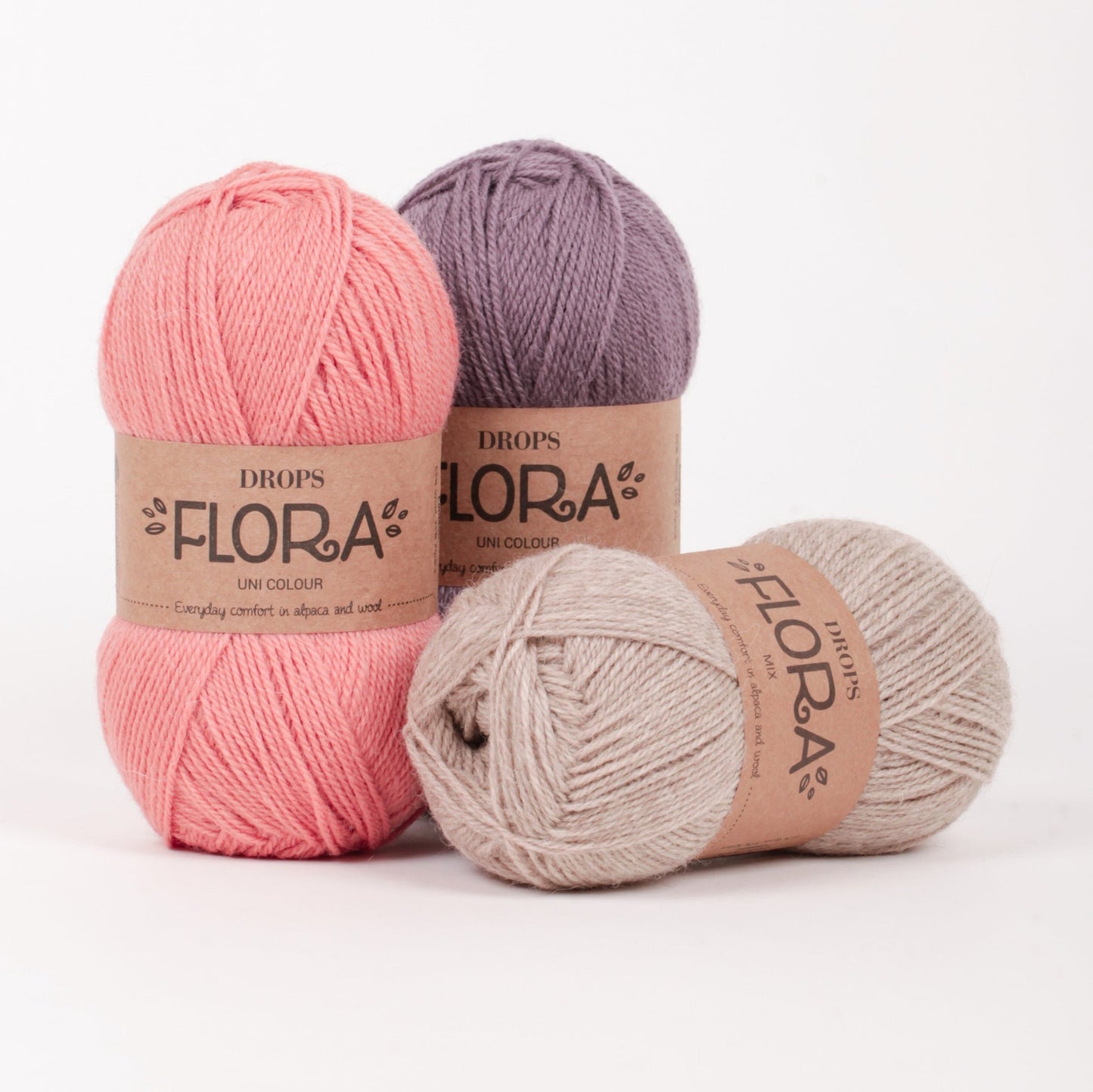 Drei Knäuel der Wolle DROPS Flora in den Farben 20 (nicht mehr erhältlich), 09 amethyst und 07 beige (von links nach rechts).