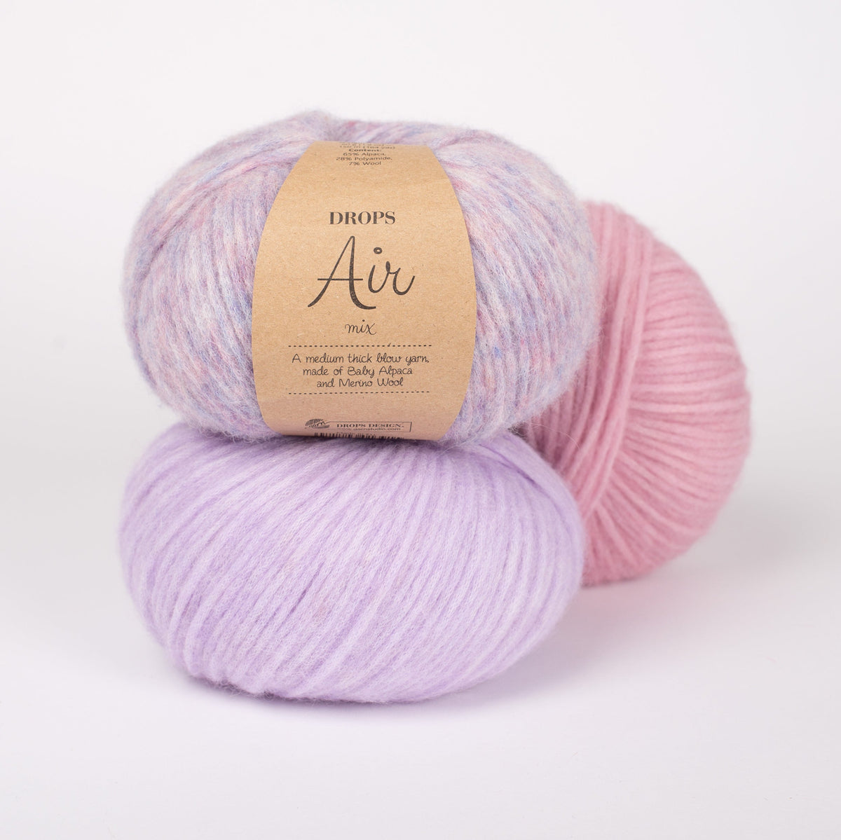 Drei Knäuel der Wolle DROPS Air in den Farben 15 lila nebel (oben), 41 zarte orchidee (unten) und 24 zartrosa (hinten).