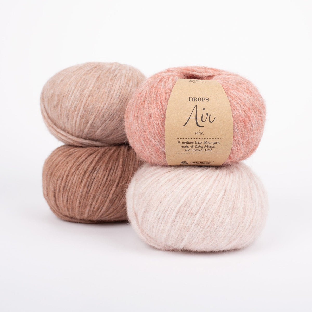 Vier Knäuel der Wolle DROPS Air in den Farben 32 blush (oben rechts), 33 rosa sand (unten rechts), 34 rosa marmor (oben llinks) und 35 ziegelstein (unten links).