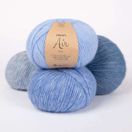 Vier Knäuel der Wolle DROPS Air in den Farben 36 hellblau (oben), 16 blau (unten), 10 nebel (links) und 17 jeansblau (rechts).