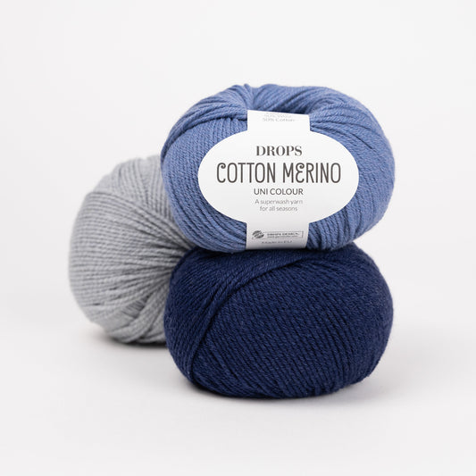 Drei Knäuel der Wolle DROPS Cotton Merino in den Farben 16 jeansblau (oben), 08 marine (unten) und 20 meereskiesel (hinten).