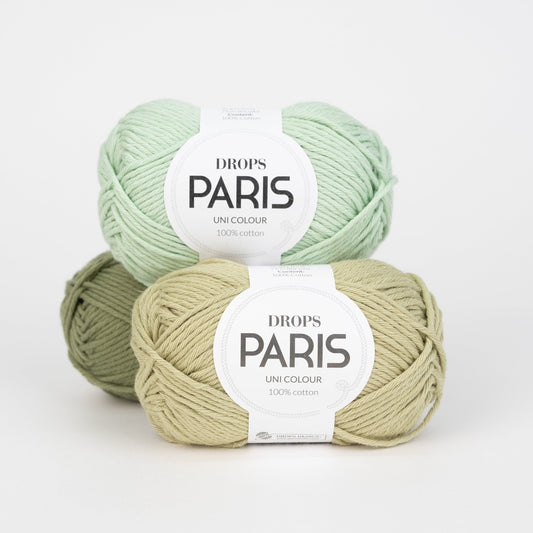 Drei Knäuel der Wolle DROPS Paris in den Farben 69 pistazie, 25 moosgrün und 21 mintgrün (von vorne über hinten nach oben).