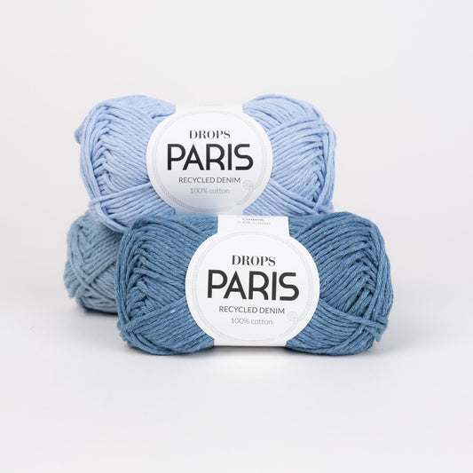 Drei Knäuel der Wolle DROPS Paris recycled denim in den Farben 100 light wash (oben), 101 hellblau (hinten) und 102 spray blue (vorne).