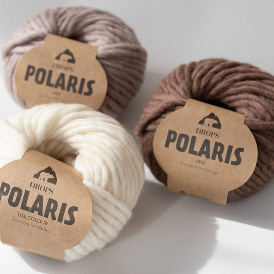 Drei Knäuel der Wolle DROPS Polaris in den Farben 01 natur (links unten), 06 hellbeige (links oben) und 14 eichel (rechts).