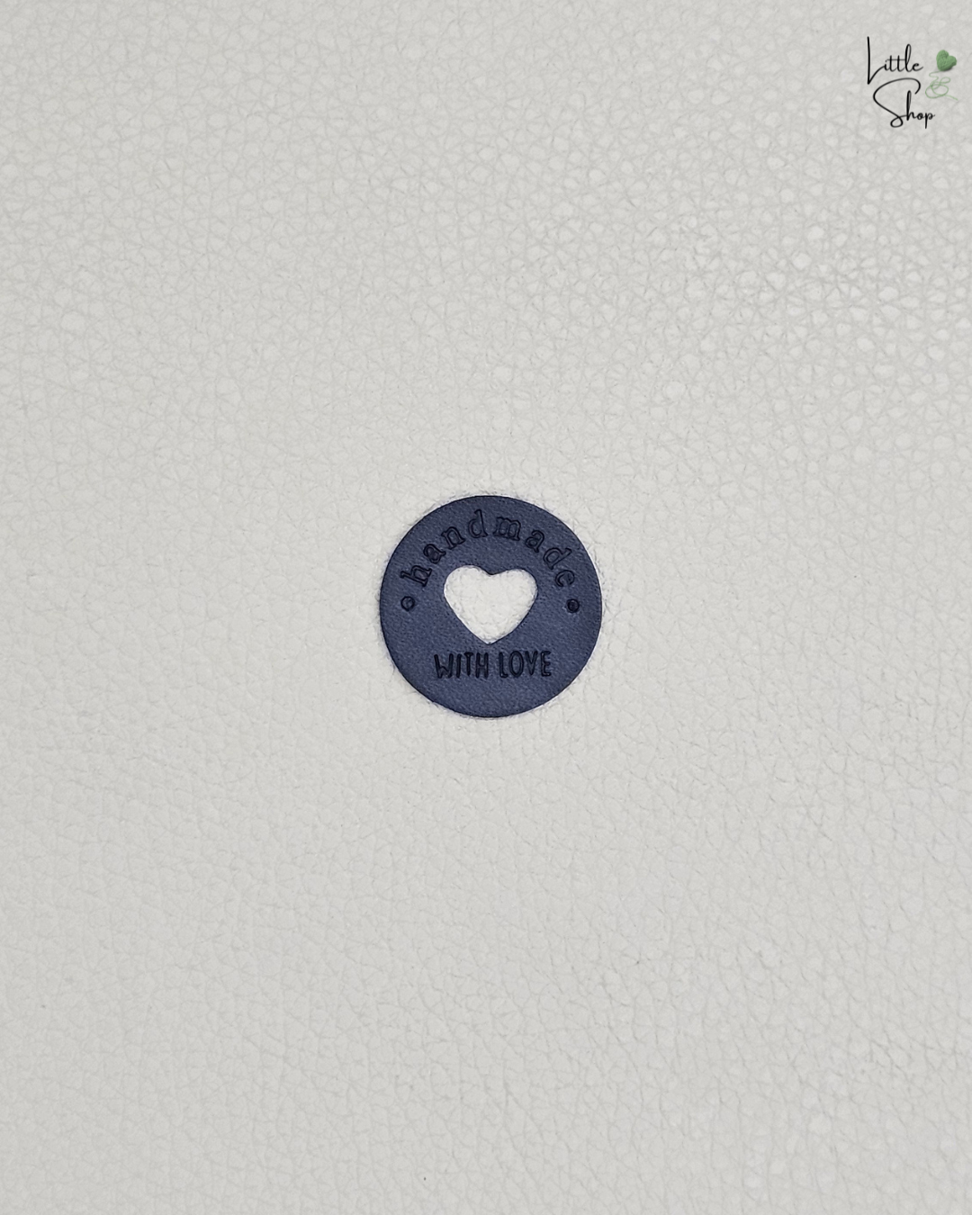 Schwarzes rundes Aufnählabel mit ausgestanztem Herz und dem Schriftzug "Handmade with love".