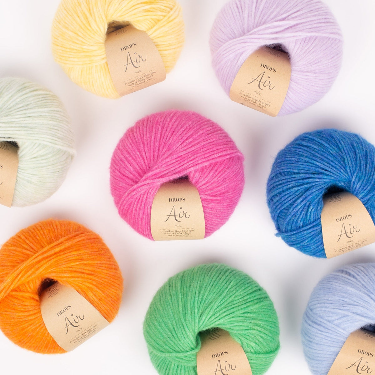 Acht Knäuel der Wolle DROPS Air in den Farben 36 hellblau, 37 blauer vogel, 41 zarte orchidee, 43 papageigrün, 39 magenta, 40 limonade, 38 elektrisches orange und 42 pistazieneis.