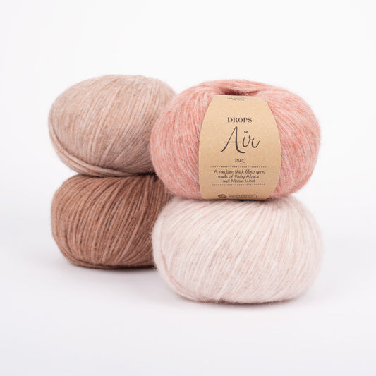 Vier Knäuel der Wolle DROPS Air in den Farben 32 blush (oben rechts), 33 rosa sand (unten rechts), 34 rosa marmor (oben llinks) und 35 ziegelstein (unten links).