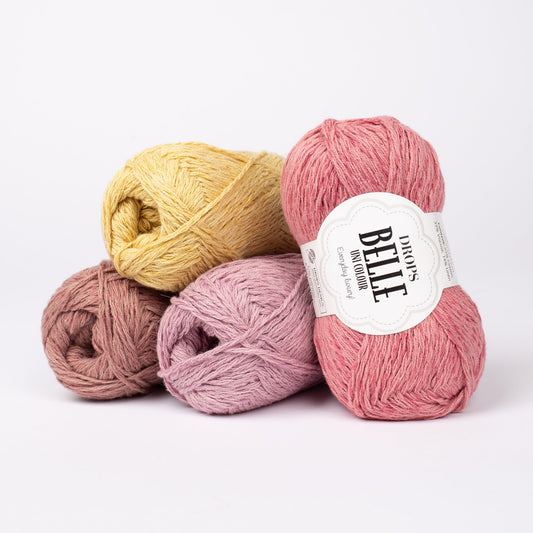 Vier Knäuel der Wolle DROPS Belle in den Farben 21 rosenmandel (links unten), 16 mauve (Mitten unten), 04 löwenzahn (links oben) und 11 altrosa (rechts).
