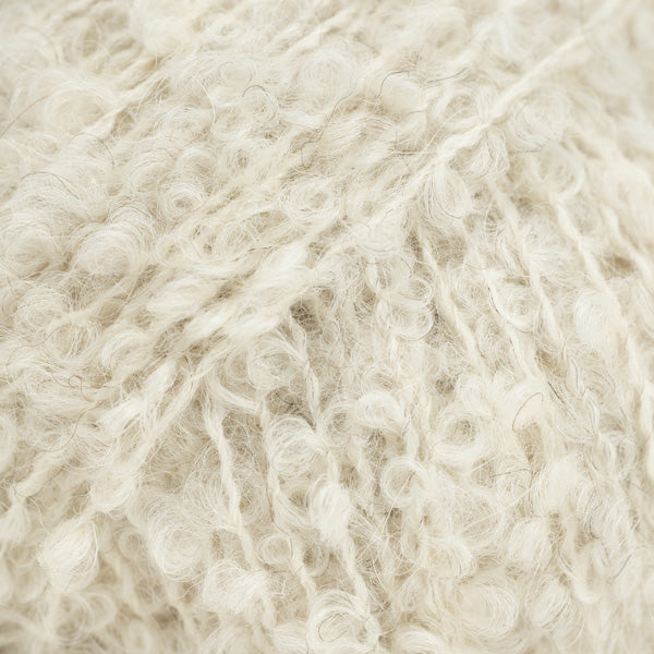 Detailaufnahme von der Wolle DROPS Alpaca Bouclé in der Farbe 8906 birke. Birke ist ein helles beige mit einigen dunkleren Fasern.