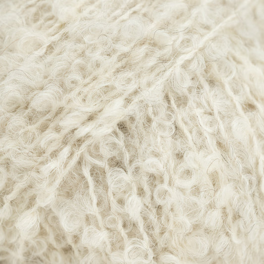 Detailaufnahme von der Wolle DROPS Alpaca Bouclé in der Farbe 8906 birke. Birke ist ein helles beige mit einigen dunkleren Fasern.