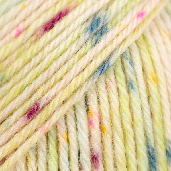 Detailaufnahme von der Wolle DROPS Fiesta in der Farbe 47 saure bonbons. Die Farbe saure bonbons hat einen cremefarbenen Grundton und viele bunte Flecken drauf. 