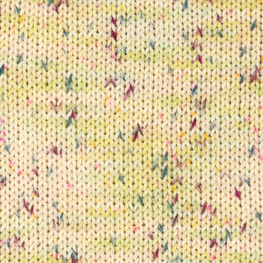 Detailaufnahme eines Strickstücks aus der Wolle DROPS Fiesta in der Farbe 47 saure bonbons. Die Farbe saure bonbons hat einen cremefarbenen Grundton und viele bunte Flecken drauf. 