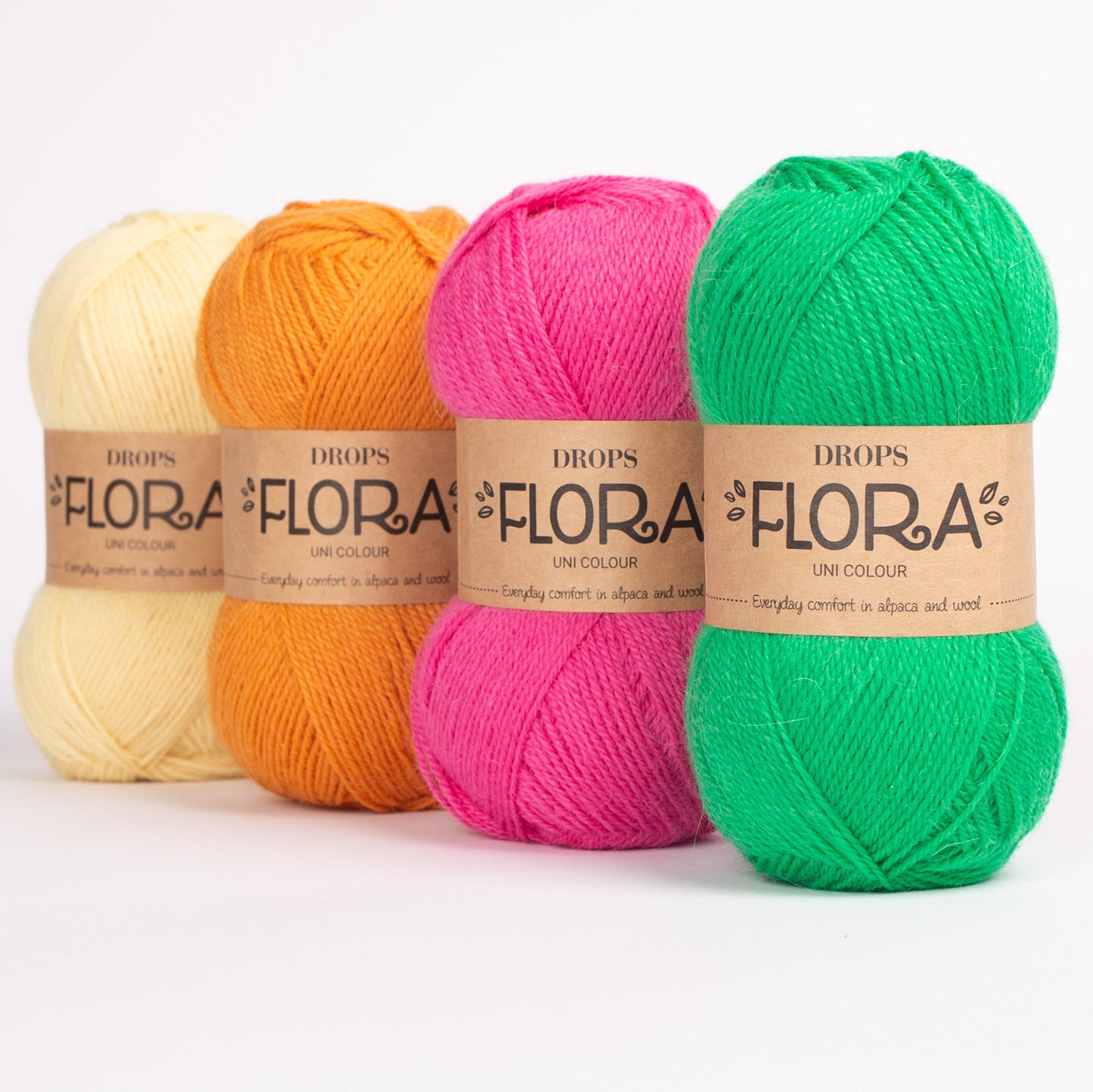 Vier Knäuel der Wolle DROPS Flora in den Farben 26 limonade, 27 (nicht mehr erhältlich), 28 magenta und 29 (nicht mehr erhältlich) (von links nach rechts). 