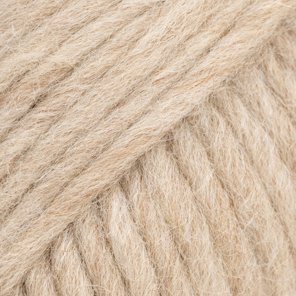 Detailaufnahme von der Wolle DROPS Snow in der Farbe 128 hafermilch. Die Farbe hafermilch ist ein cremig-beiger Farbton.