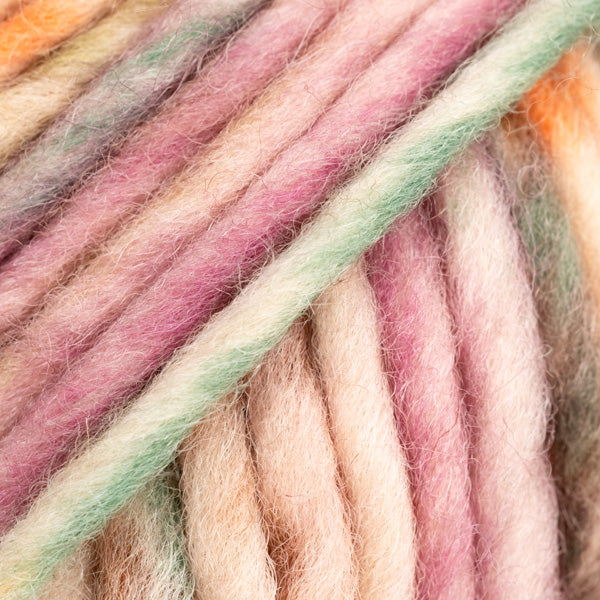 Detailaufnahme von der Wolle DROPS Snow in der Farbe 142 herbstkräuter print. Die Farbe besteht aus cremefarbenen, orangen, braunen und dunkelrosafarbenen Abschnitten.