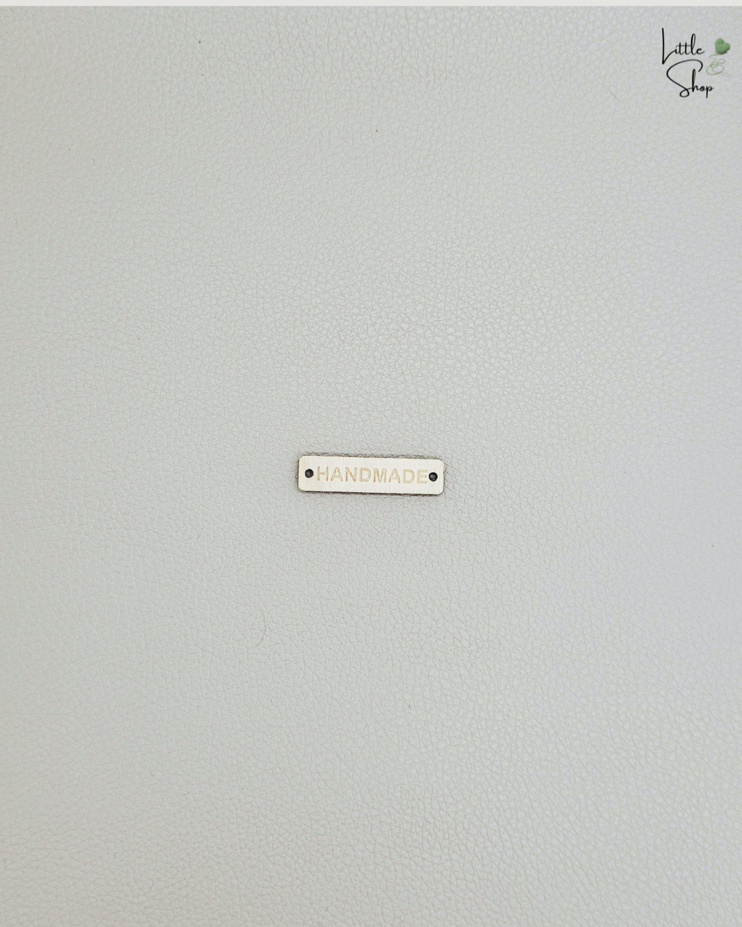 Kleines rechteckiges Label aus Holz mit dem Schriftzug "Handmade" und zwei Löchern, um es anzunähen.