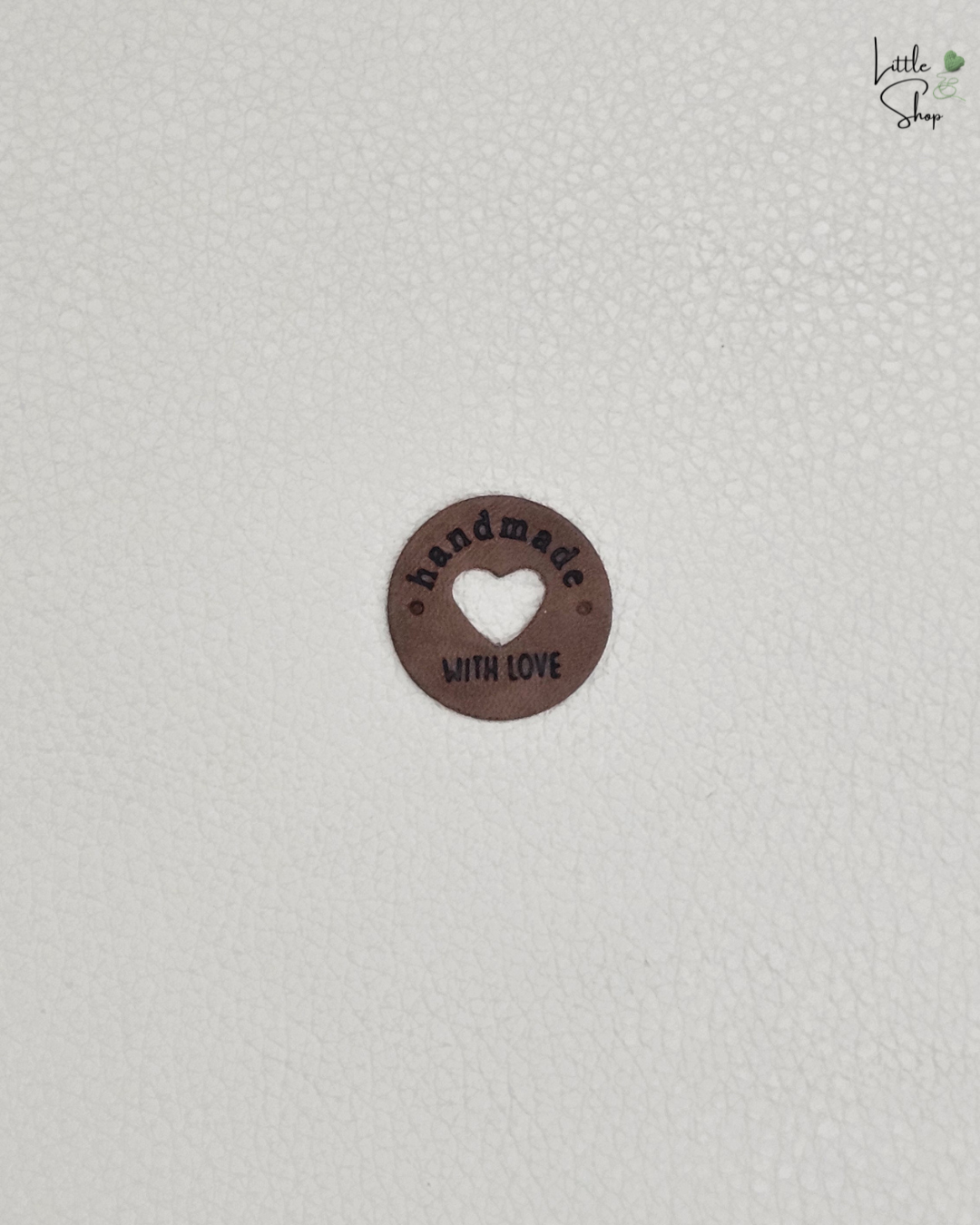Braunes rundes Aufnählabel mit ausgestanztem Herz und dem Schriftzug "Handmade with love".