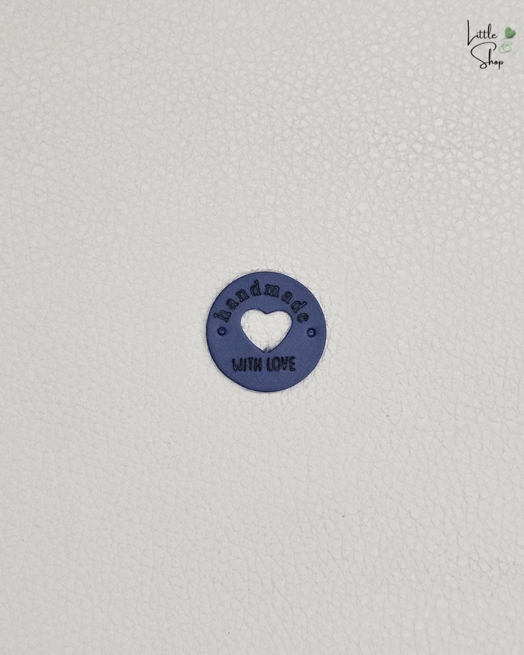 Dunkelblaues rundes Aufnählabel mit ausgestanztem Herz und dem Schriftzug "Handmade with love".