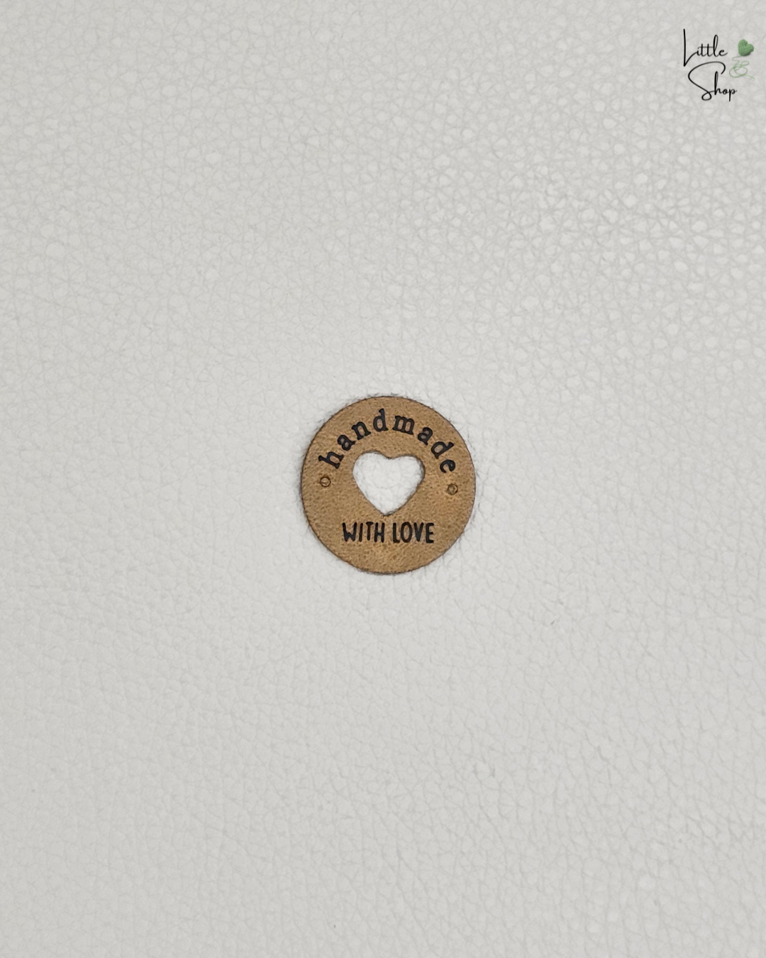 Mittelbraunes rundes Aufnählabel mit ausgestanztem Herz und dem Schriftzug "Handmade with love".