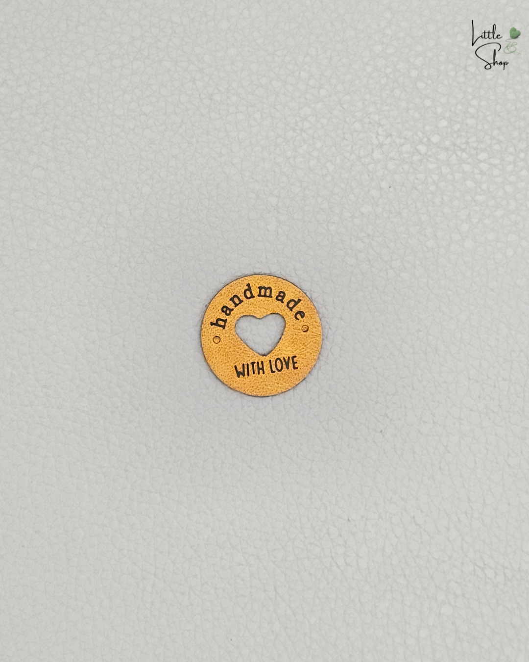 Oranges rundes Aufnählabel mit ausgestanztem Herz und dem Schriftzug "Handmade with love".