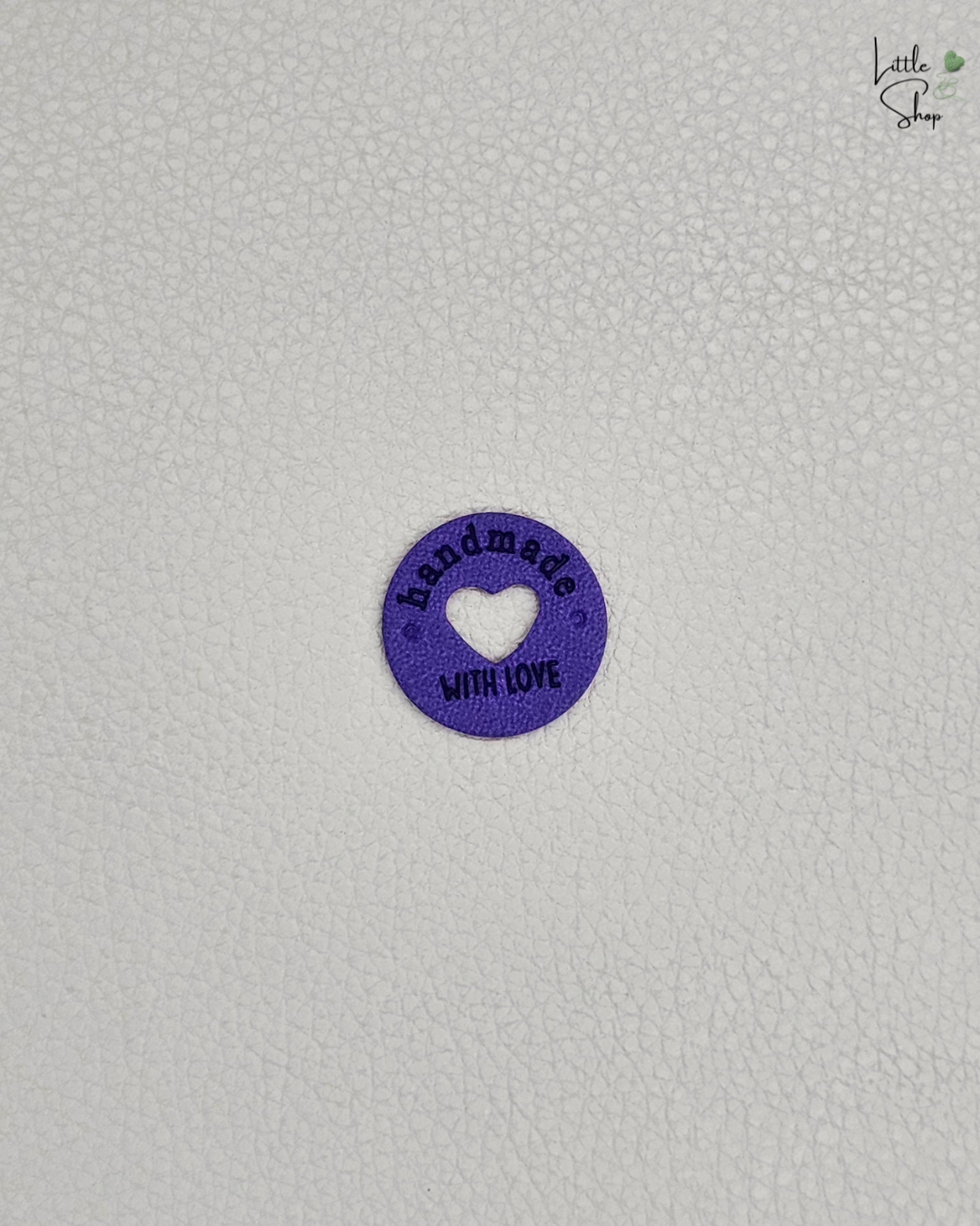 Violettes rundes Aufnählabel mit ausgestanztem Herz und dem Schriftzug "Handmade with love".